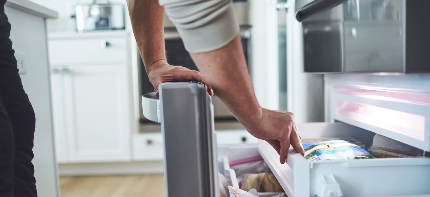 Unidentified person leaning down into the freezer draw looking for frozen tofu