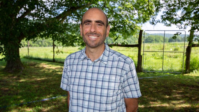 Love.Life Telehealth Founder Anthony Masiello stands beneath the shade of a tree, with a green pasture behind him