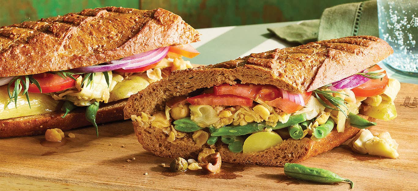 A close-up of two warm, stuffed baguette Vegan Niçoise Salad Sandwich (Pan Bagnat)