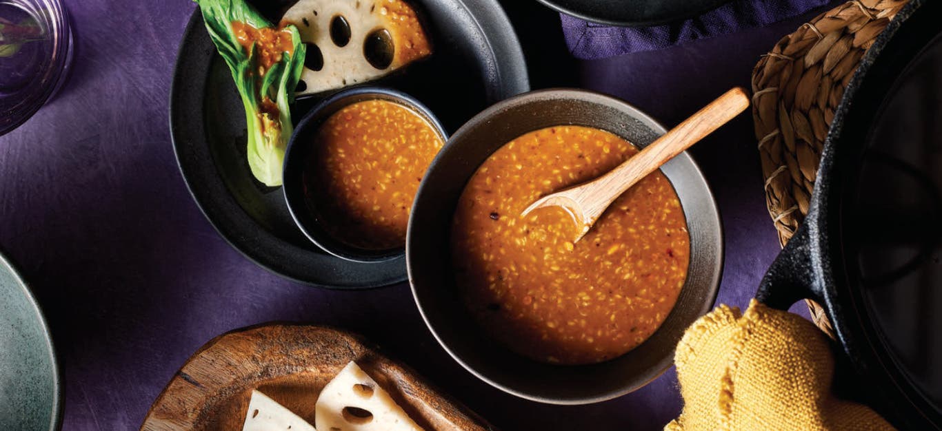 A bowl Peanut-Sesame Dipping Sauce next to a plate with a smaller bowl of sauce and bok choy