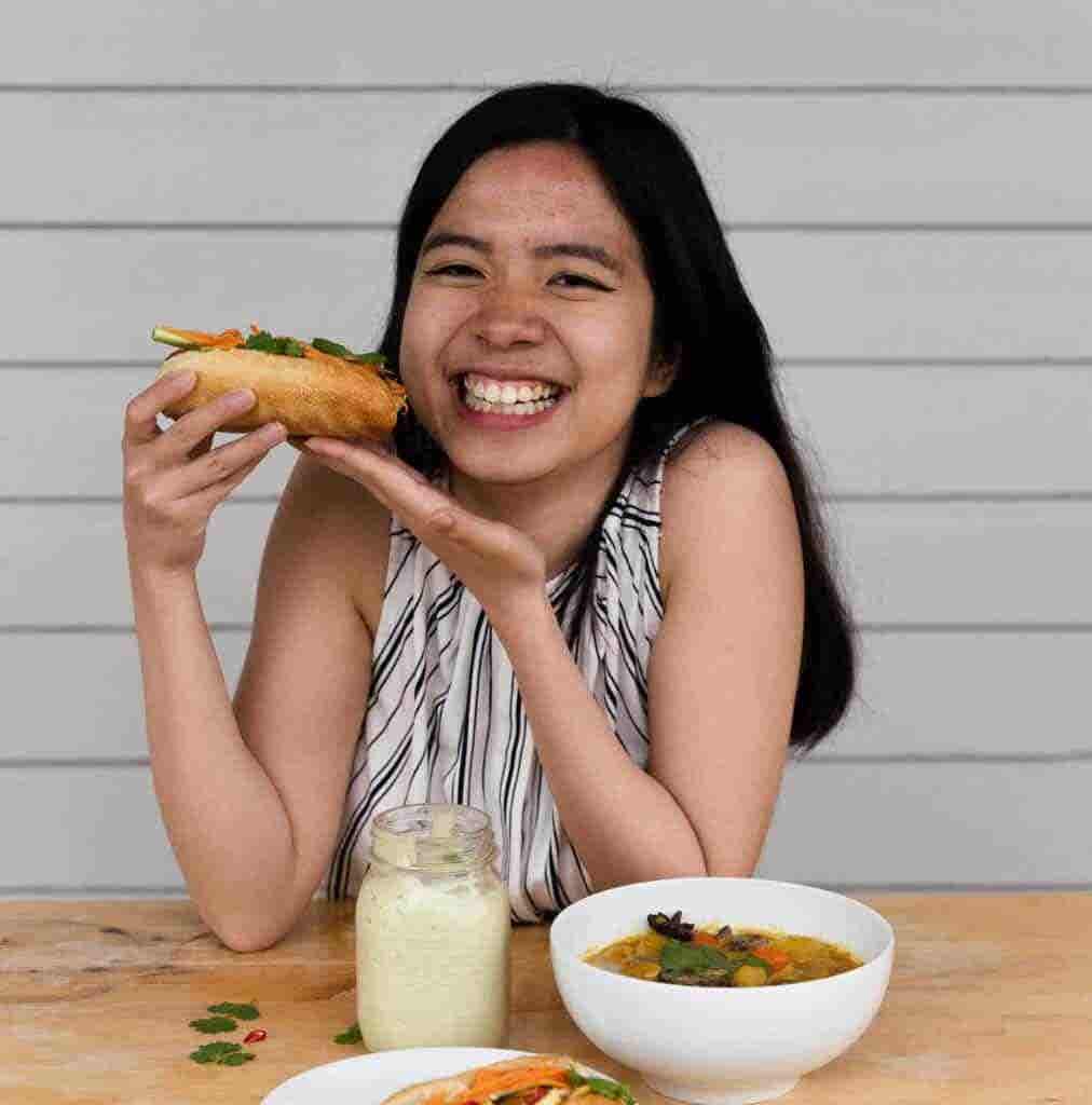 Food blogger Veggie Anh Tran eats a vegan banh mi sandwich and smiles