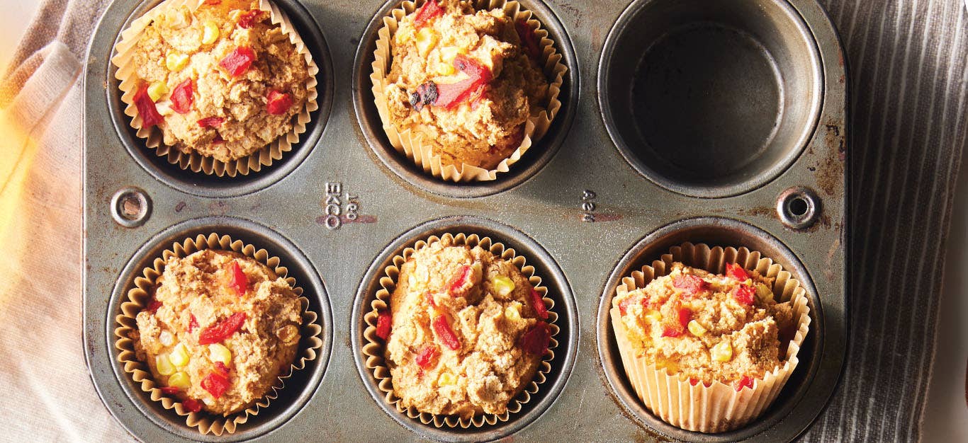 A muffin try zoomed in on 5 Cornmeal Muffins specked with red and yellow