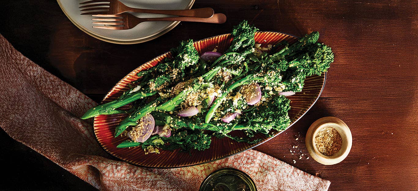 A red platter of Ginger-Sesame Broccoli Rabe Salad with shallots dotted throughout