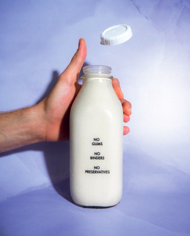 a hand flicks the cap off a bottle of milk - photo from breaking up with dairy by bailey ruskus