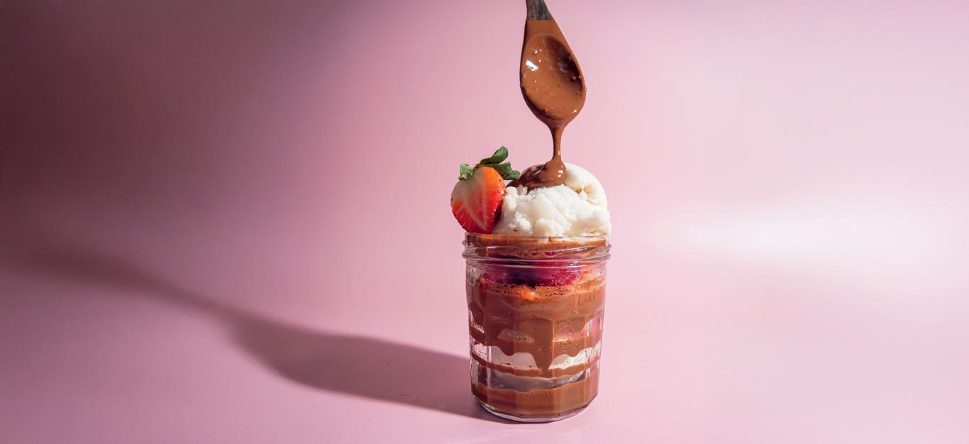 Chef Bai's Oat Chocolate Put-on-Everything Sauce drizzled over a tall glass of ice cream and strawberries