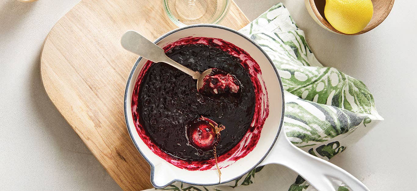 Looking down on a white pot of Small-Batch Blueberry Jam Without Pectin, with a spoon in the pot