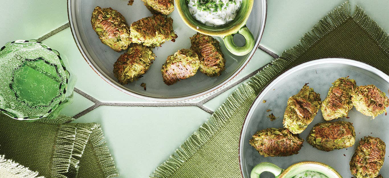 Two plates with Potato and Broccoli Tots , each plate has a small bowl of creamy white dipping sauce