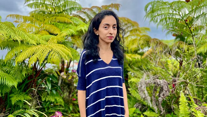 Gastroenterologist Shilpa Ravella poses in front of a lush backdrop of ferns near her home in Hawaii