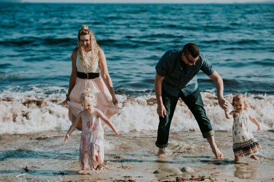 Chris Noel with his wife and two children, playing in the surf at the beach