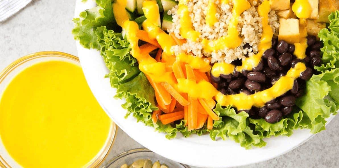 24-Carrot Gold Dressing in a small bowl next to a larger grain bowl drizzled with the dressing