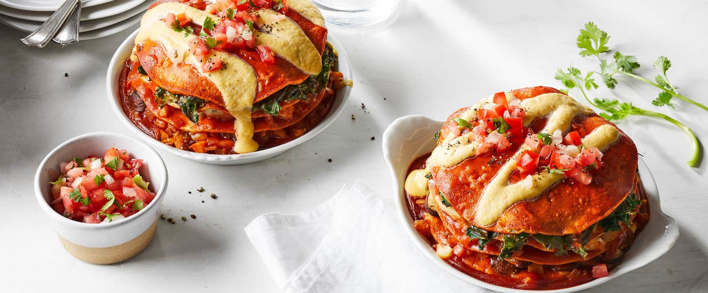 Two stacks of 4-Layer Enchilada Cakes with a small bowl of salsa