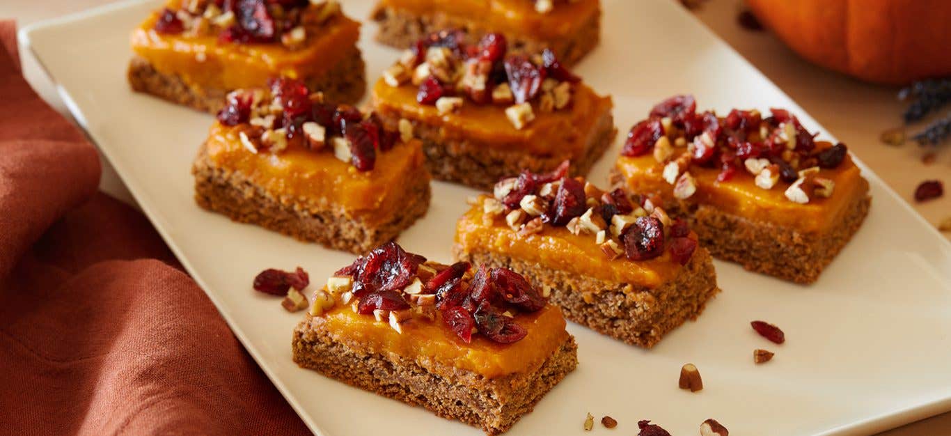 A white serving platter with Almond-Oat Cookie Bars with Pumpkin Frosting, spaced so there is room between each piece