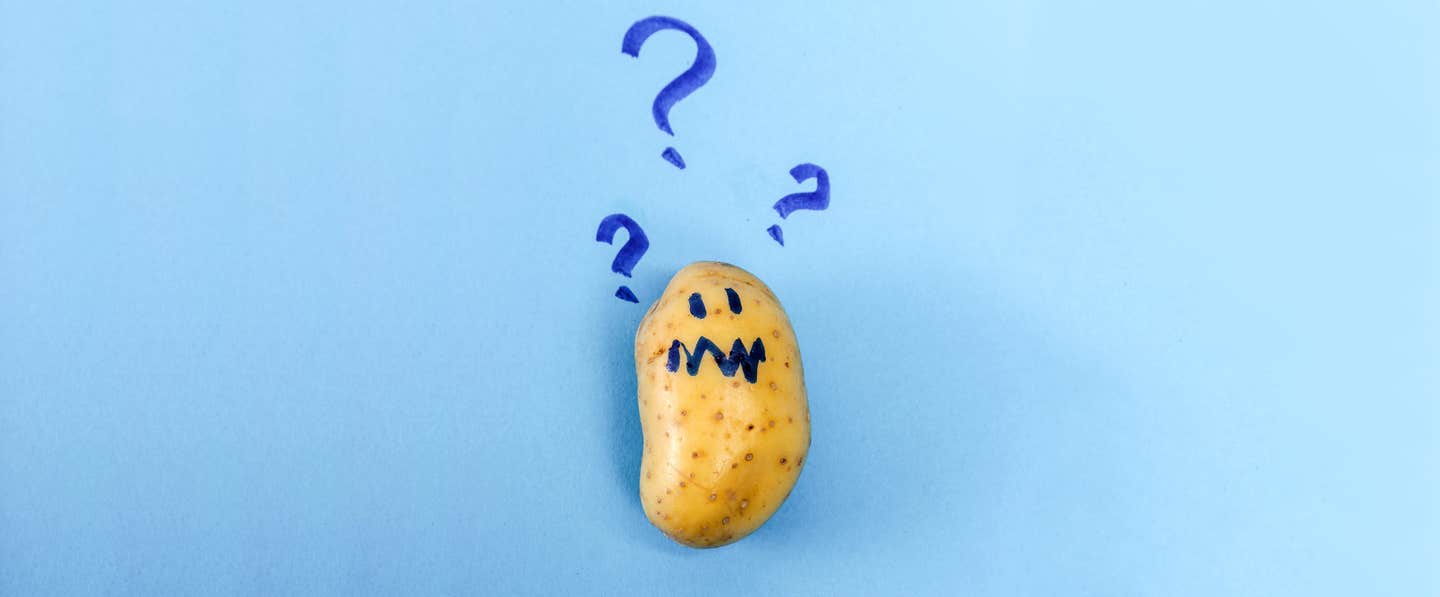 Raw potato on a blue background. Hand drawn blue question marks are above the potato. The potato has a worried face drawn on it in the same blue pen.