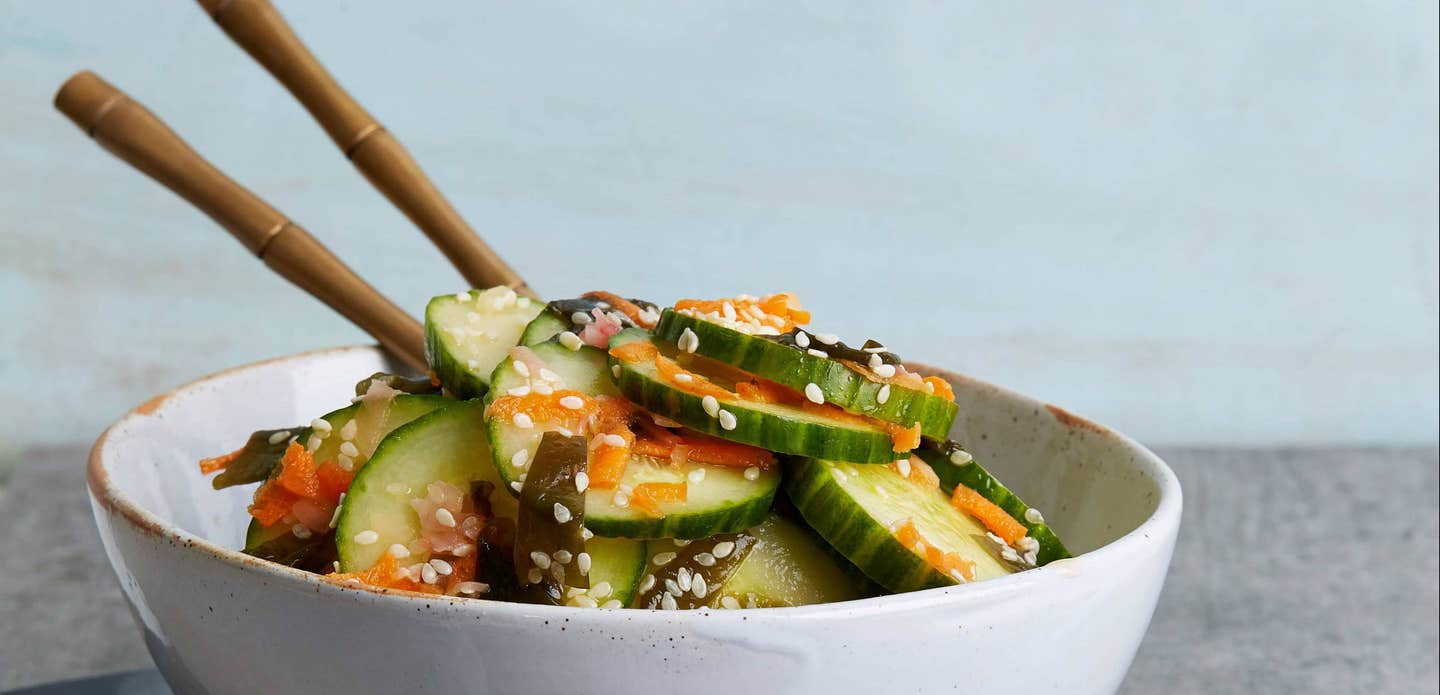 Asian Cucumber and Sea Vegetable Salad in a white bowl with chopsticks sticking out of the bowl