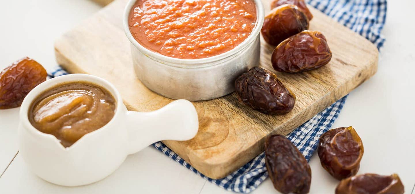 Easy Date Barbecue Sauce on a wooden chopping board with dates and a small jug of date paste