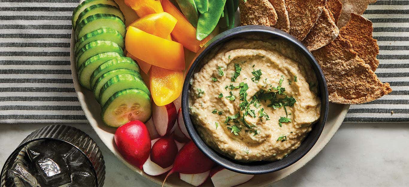 Oil-Free Baba Ghanoush in a small gray bowl surrounded by fresh veggies and crackers