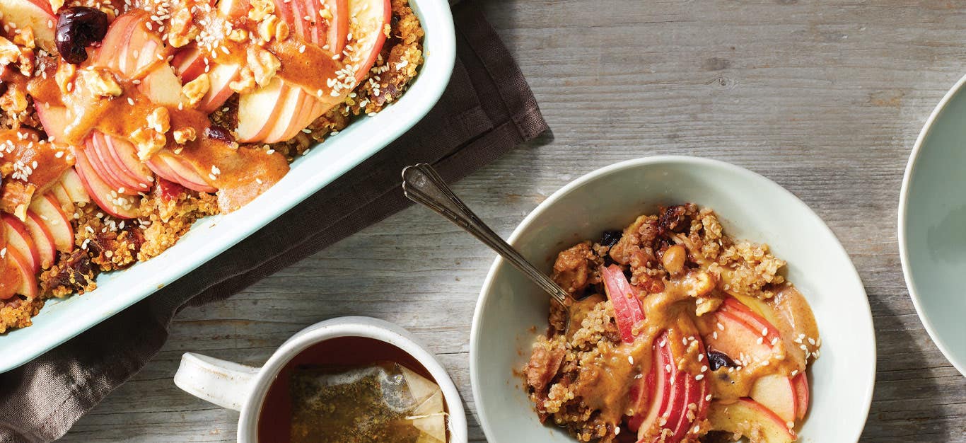 Quinoa and Apple Breakfast Casserole with Cherry Drizzle in a white bowl next to a white casserole dish