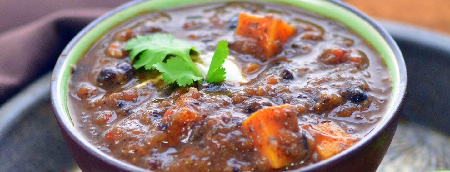 Close-up of Black Bean and Sweet Potato Soup with a sprig of flat-leaf parsley