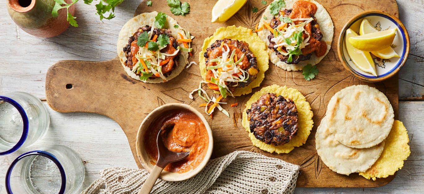 Black Bean and Plantain Burgers with Salvadoran Corn Tortillas on a wood cutting board