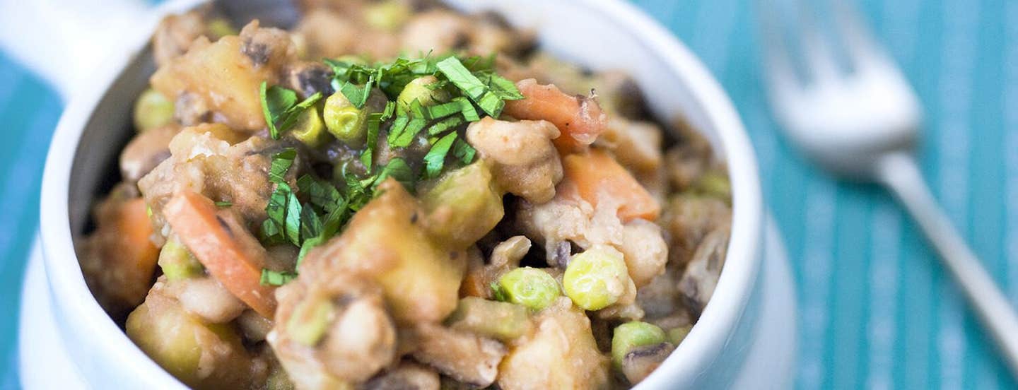 Close up of Black-Eyed Pea BBQ Stew in a white bowl with a fork out of focus in the background