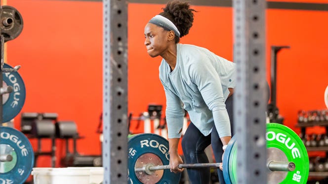 Vegan CrossFit athlete Briana Jones deadlifting weights in a gym as she prepares to compete in the Mr America competition as part of the Vegan Strong Plantbuilt team