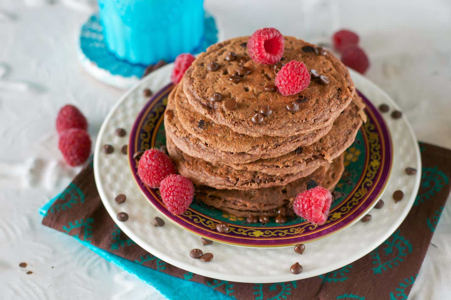 A stack of Chocolate Buttermilk Pancakes topped with vegan chocolate chips and fresh raspberries