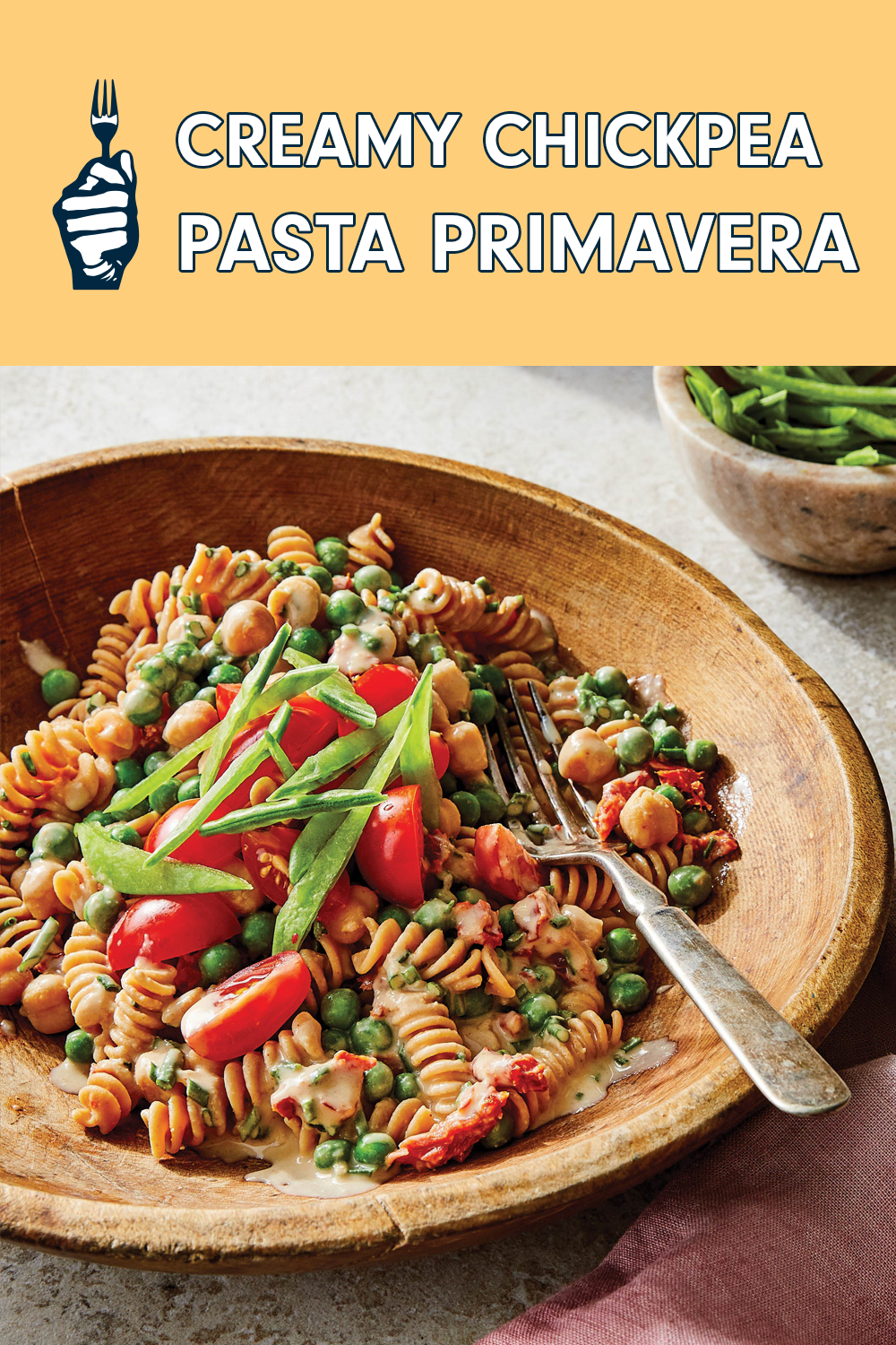 At the top of the page a header reads, "Creamy Chickpea Pasta Primavera." At the bottom is a rustic bowl of spiral pasta with tomatoes, peas, and sliced scallions