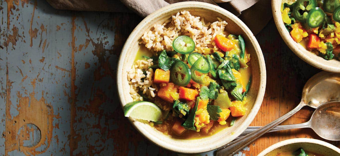 Curried Butternut Squash and Cauliflower Stew in white bowls against a brown and blue tabletop