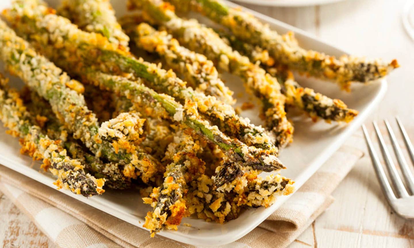 Herb-Crusted Asparagus Spears on a white serving platter with a fork to the side