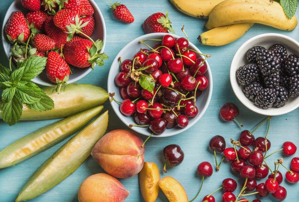 Healthy summer fruit variety on blue wooden backdrop