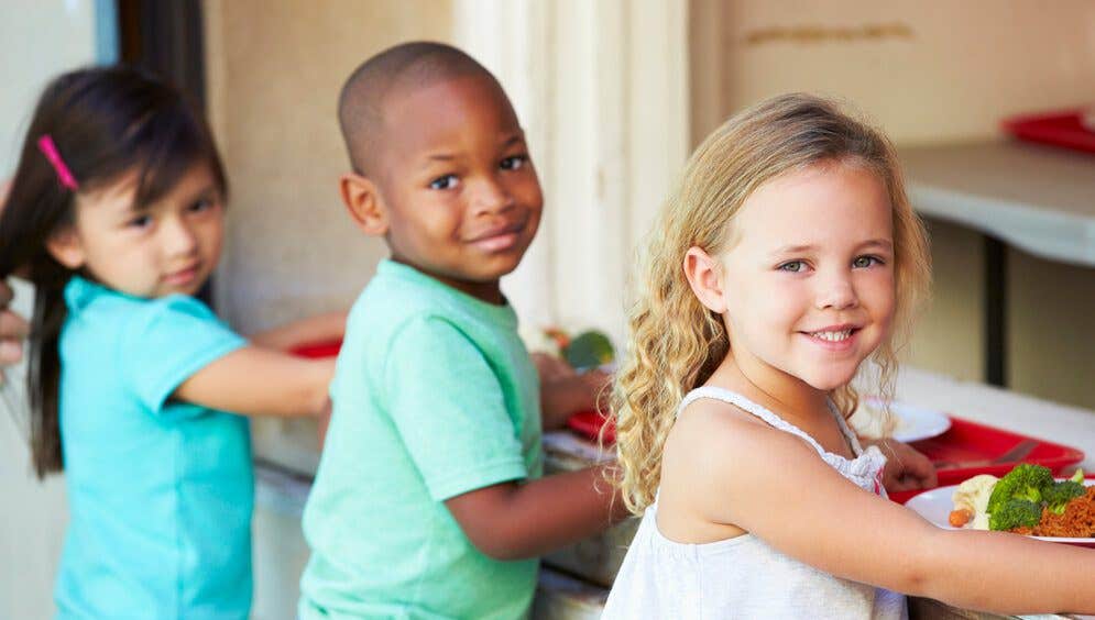 Three Elementary Pupils Collecting Healthy Lunch In Cafeteria