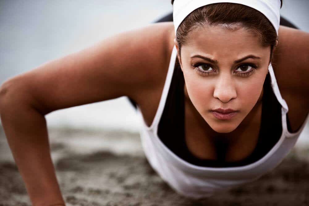 A young woman looking into the camera while doing a push up