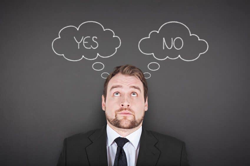 Man against a blackboard looking up at two chalk-drawn thoughts bubbles. one says yes and the other says no.