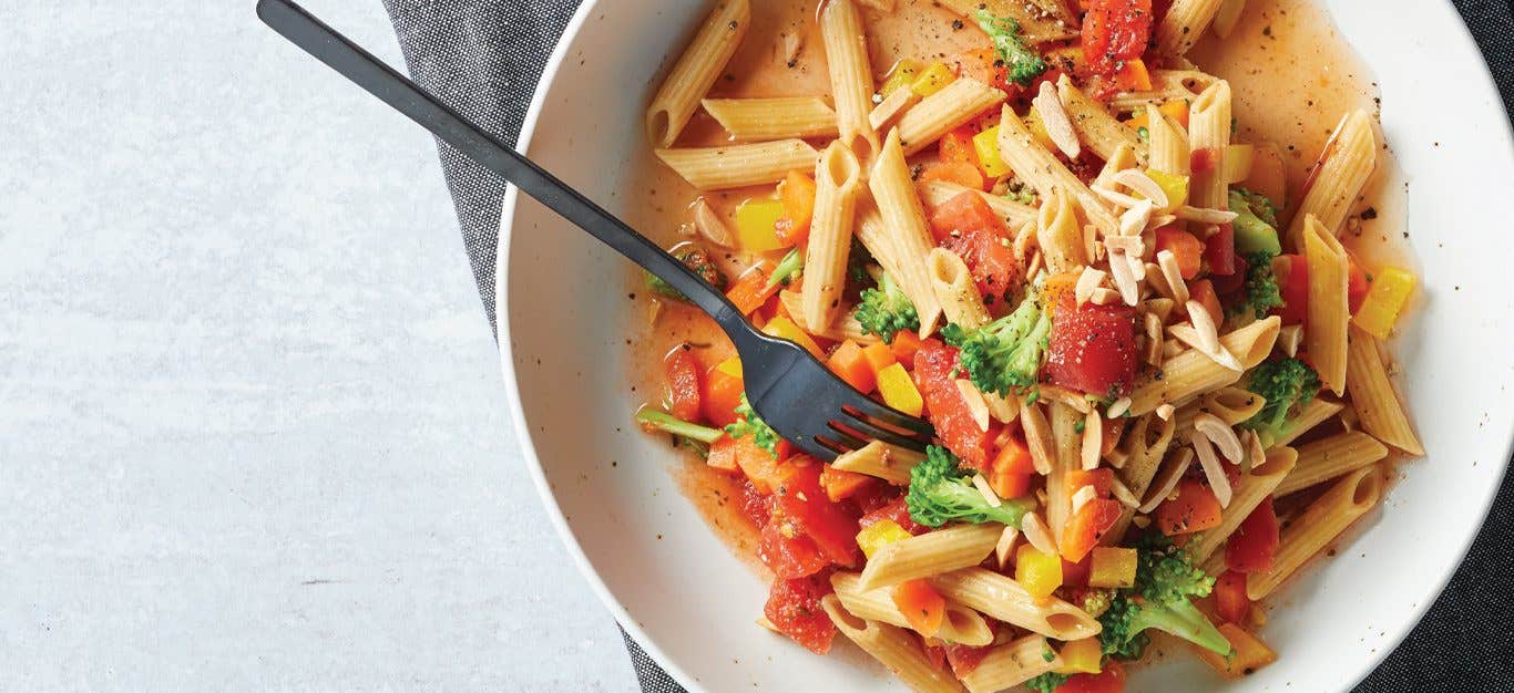 Microwave Pasta Primavera in a white bowl with metal fork