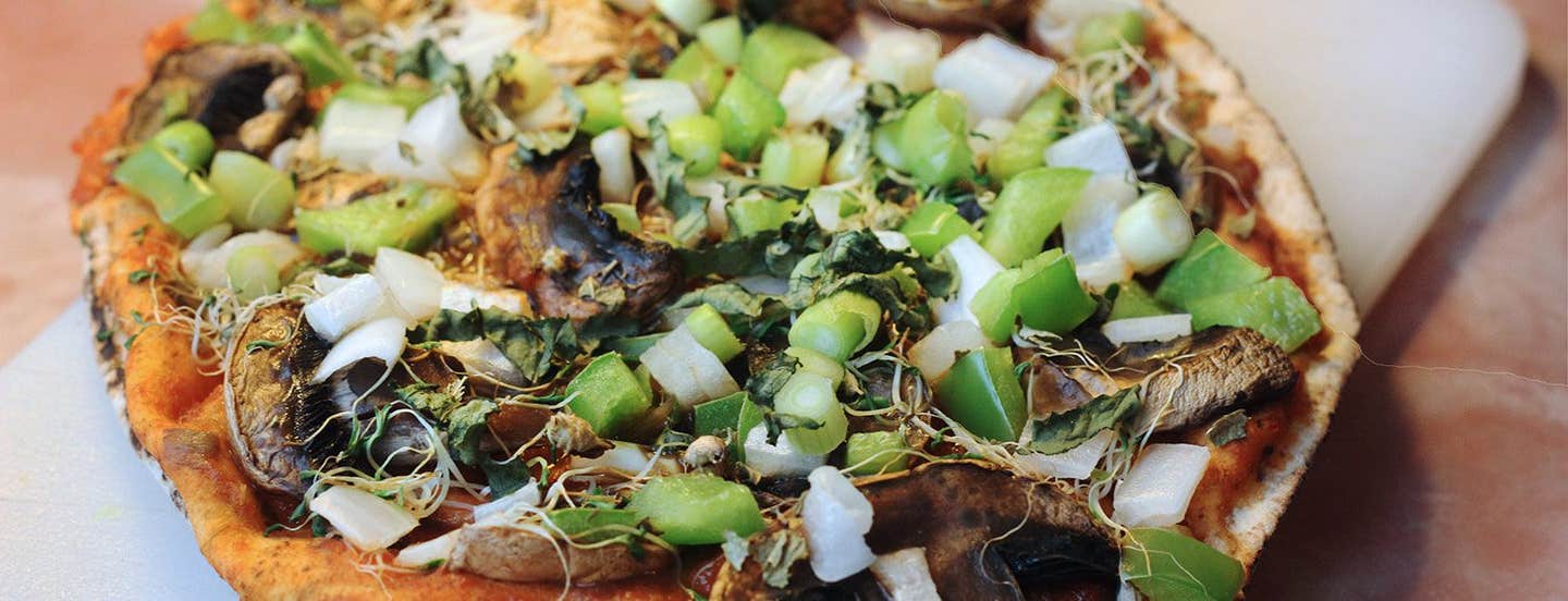 A pita bread pizza topped with green bell pepper, sprouts, mushrooms, and onion. Aka, "Fast Pizza"