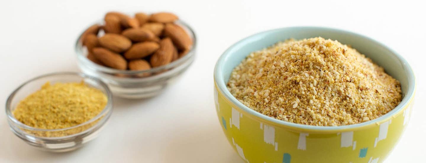 Faux Parmesan in a small colorful yellow bowl next to two smaller pinch bowls of nutritional yeast and whole almonds