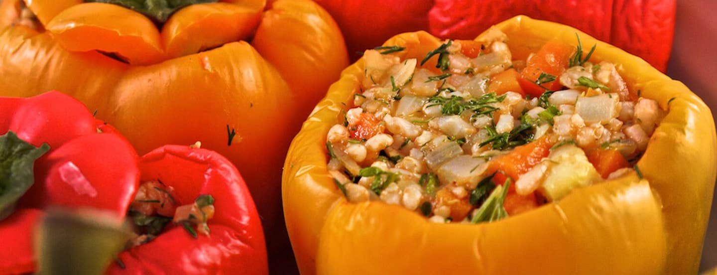 Red and orange Greek stuffed bell peppers filled with a hearty mix of veggies and brown rice