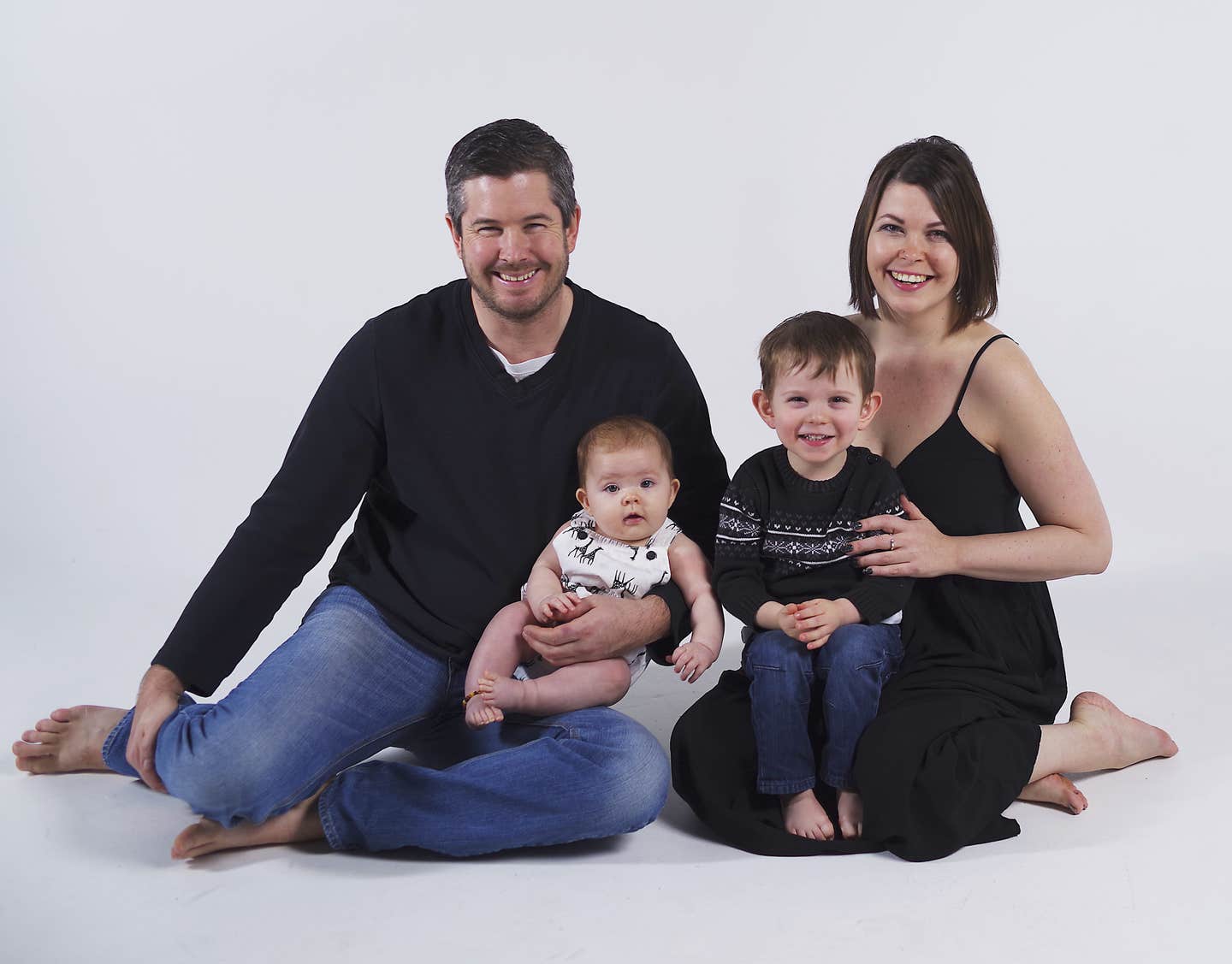 Jennifer Sinyerd and her husband sitting on the ground with their two young children