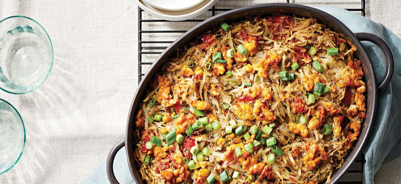 Vegan Hash Brown Casserole with Tempeh Crumbles in an oval cast iron skillet on a metal cooling rack