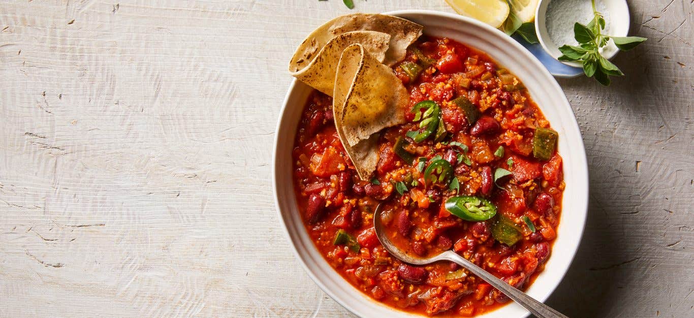 Hearty Red Bean Chili in a white bowl with tortillas on the side