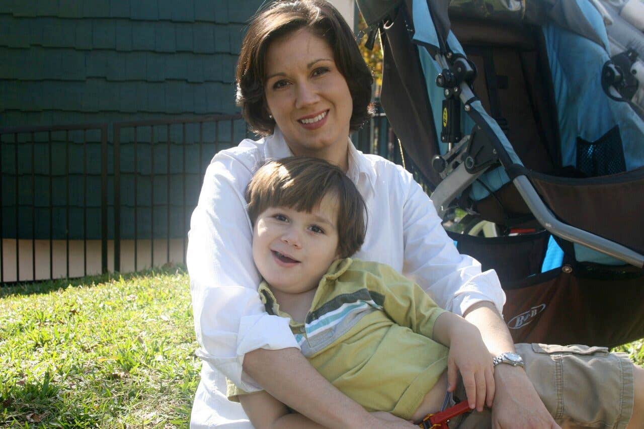 Shelly Vincent sits on the lawn with her young boy on her lap