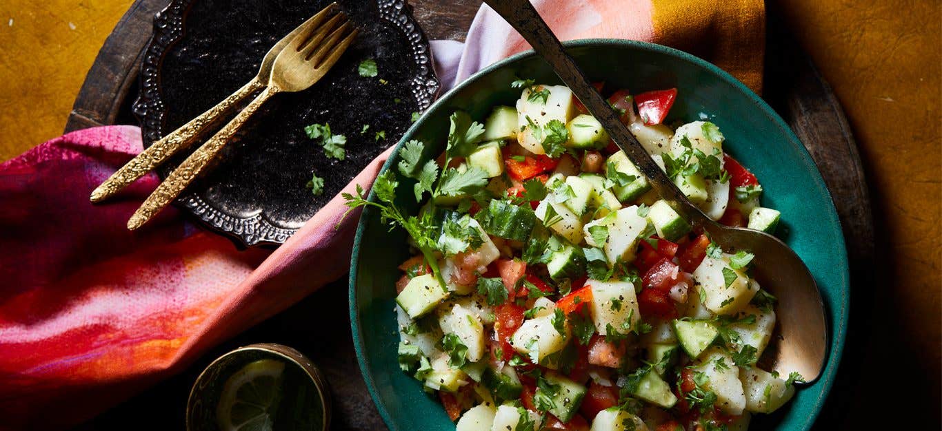 Indian-Spiced Potato Salad in a blue bowl with metal serving spoon