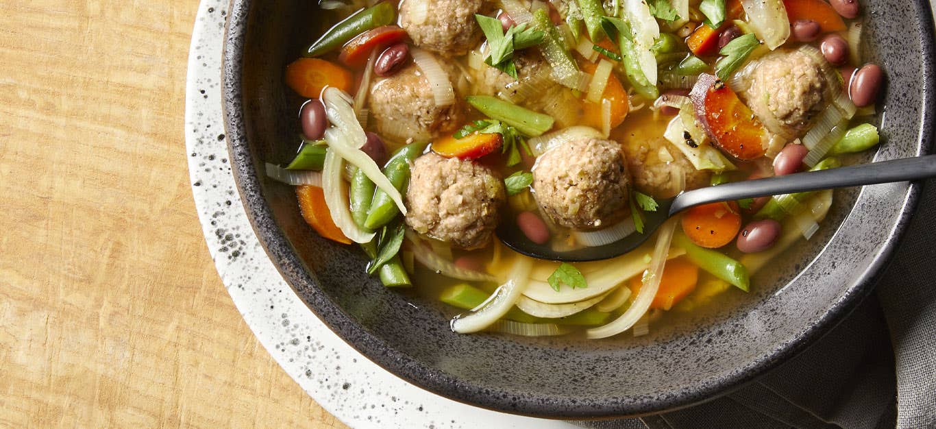 Vegan Italian Wedding Soup in a gray bowl against a wooden tabletop