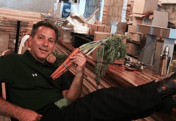 Dr. Joel Kahn at the Greenspace Cafe holding a bunch of fresh carrots