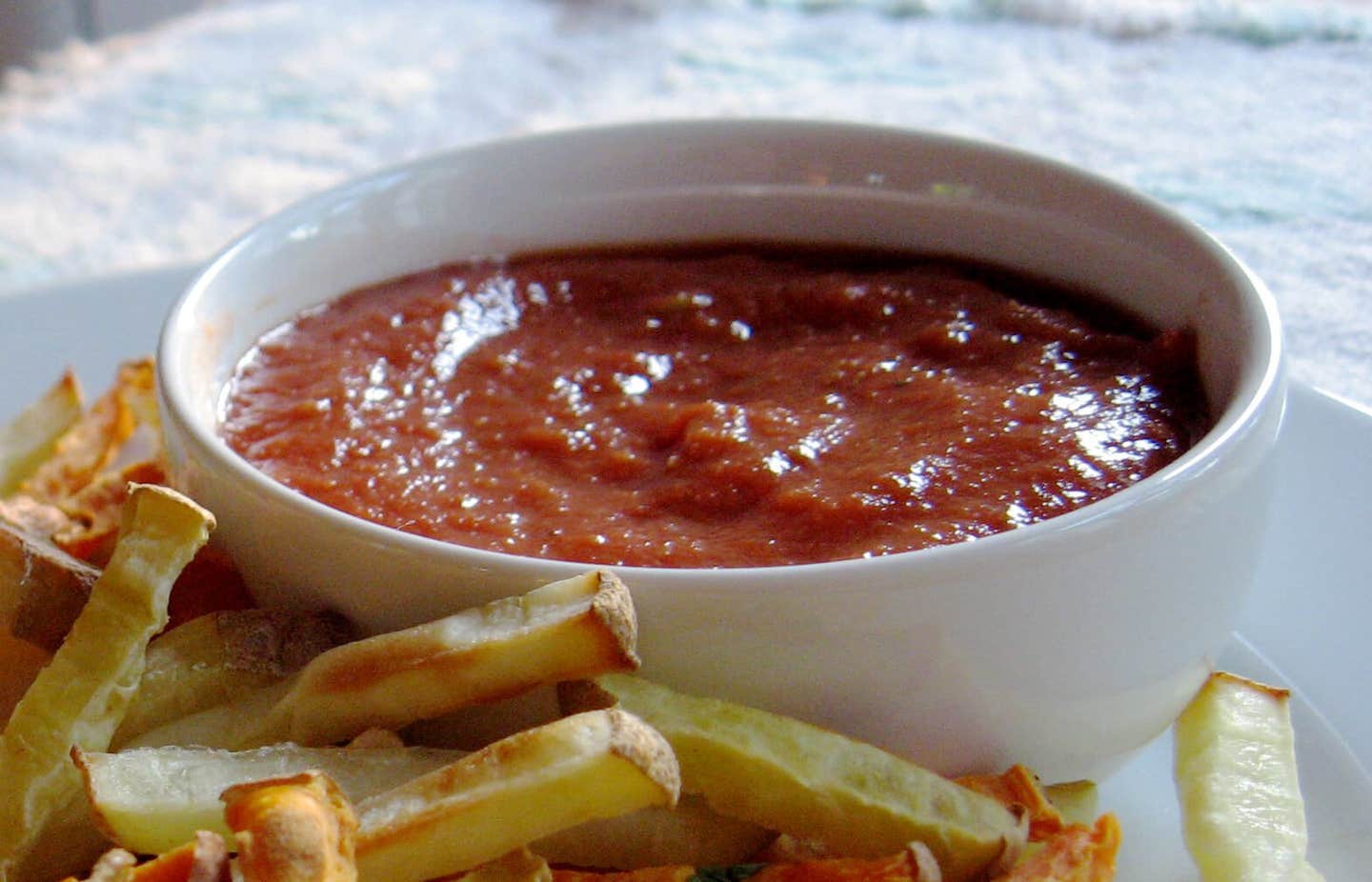 5-Minute Ketchup in a white bowl with baked oven chips surrounding