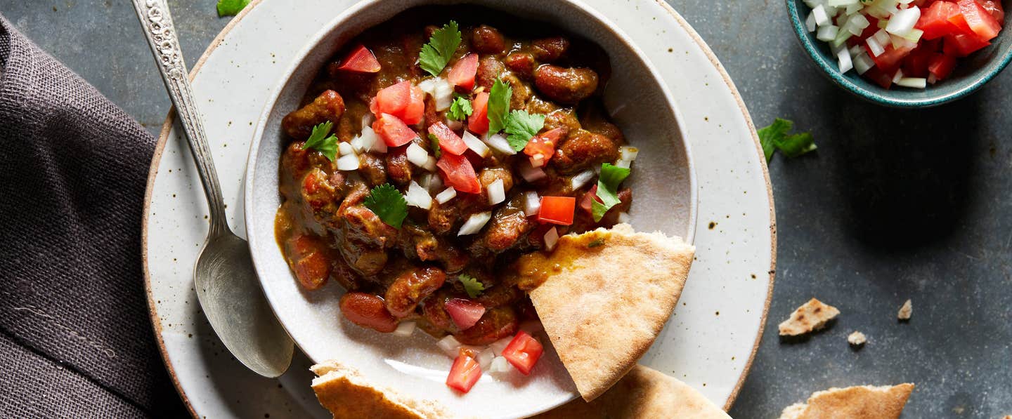 Instant Pot Kidney Bean Dal in a white bowl with a corner of pita bread and small spoon on the side