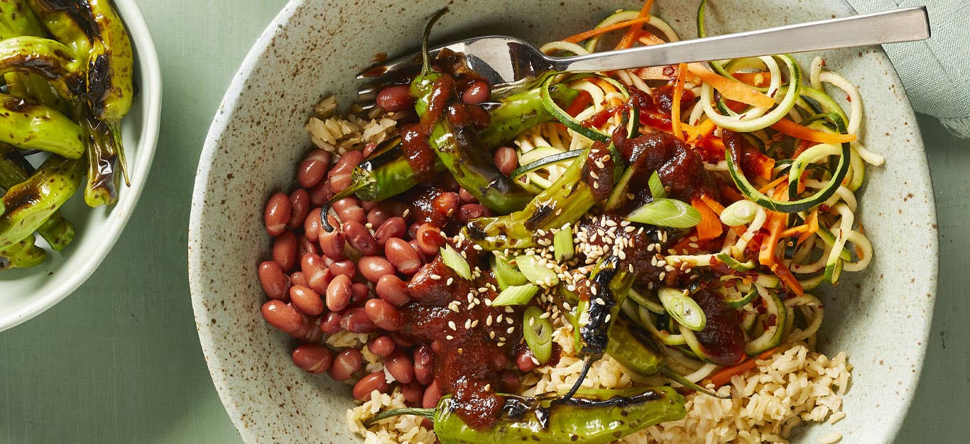 Vegan Korean BBQ Bowls with Shishito Peppers in a white ceramic bowl with a metal fork against a light green background