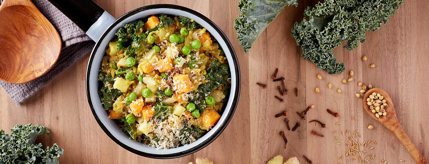 Vegan Kichadi on a wooden table with fresh cloves and kale