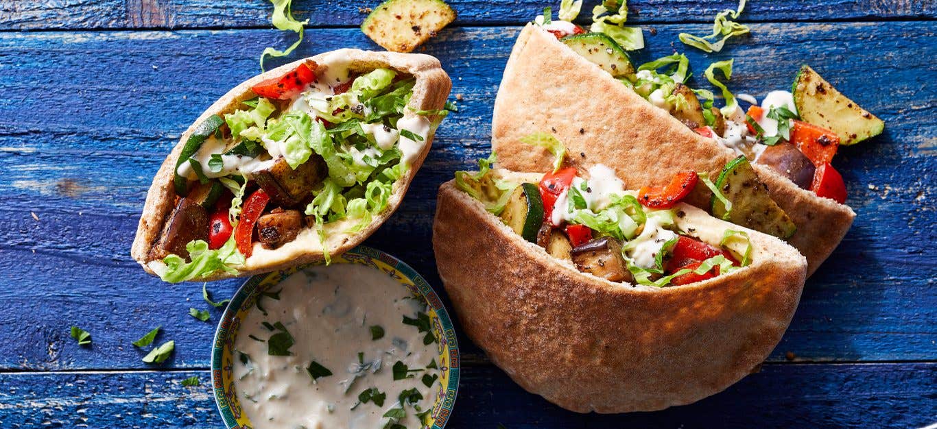 Middle Eastern Pita Pocket Sandwiches with a bowl of tahini sauce on blue wooden table