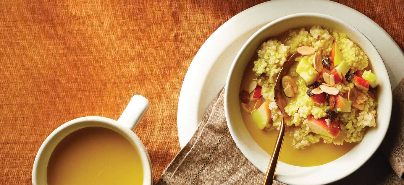 Golden Milk Millet Porridge in a white bowl with a mug of golden milk to the left